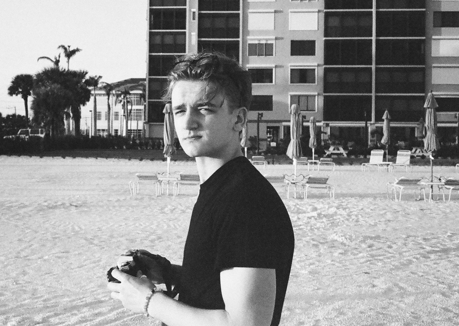 Black and white photograph on a sandy beach with high-rise buildings in the background.
