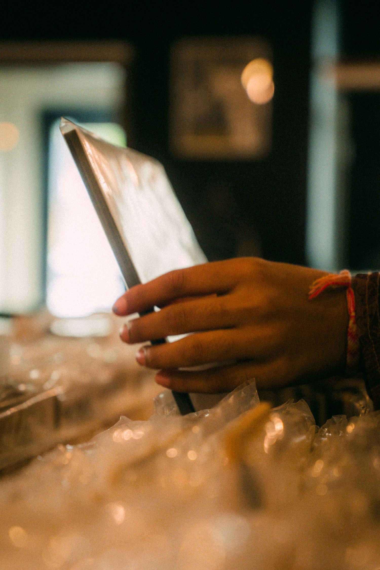 Hand holding a glowing device in a dimly lit setting.