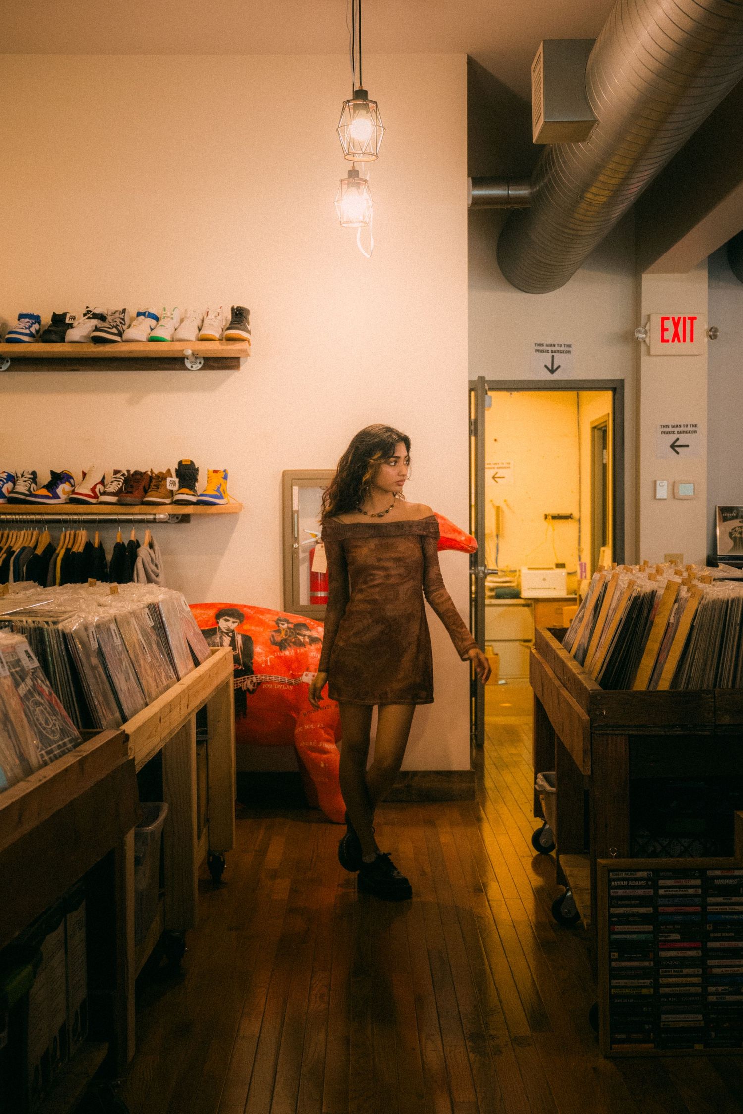 A record store interior with vinyl albums on shelves and wooden flooring lit by pendant lights.