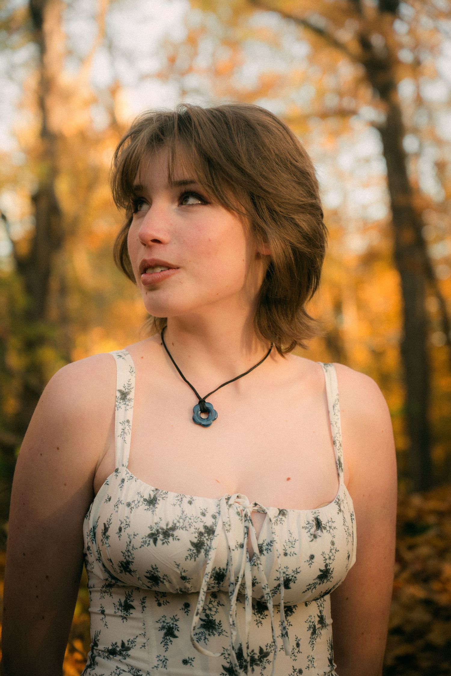 An autumn outdoor portrait with warm golden light filtering through trees.