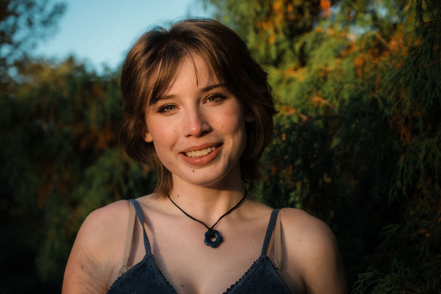 Portrait in natural setting with autumn foliage and warm lighting.