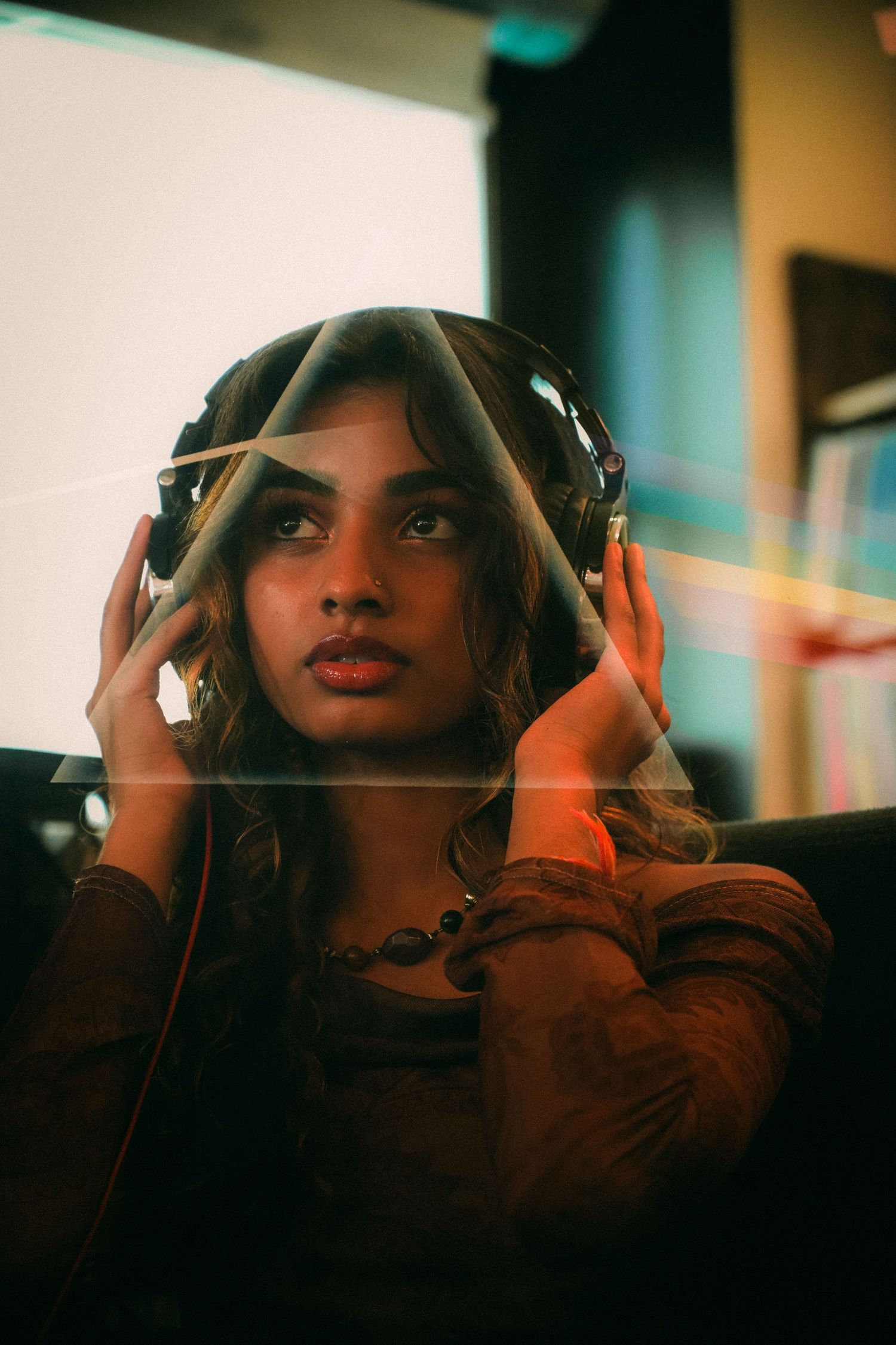Person in brown attire wearing headphones against a warm-toned background.