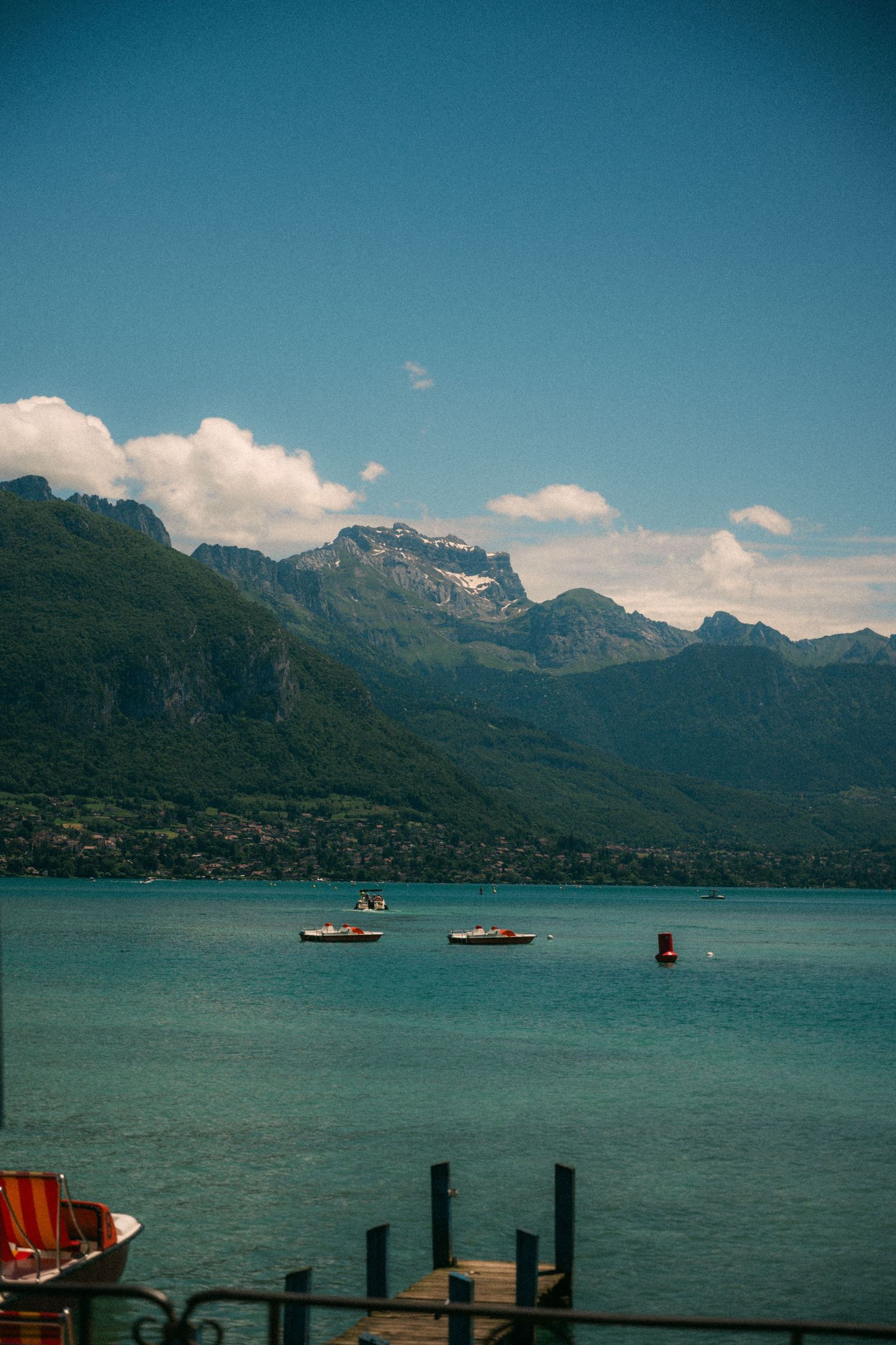 Scenic mountain lake view with small boats dotting the turquoise waters against dramatic peaks.