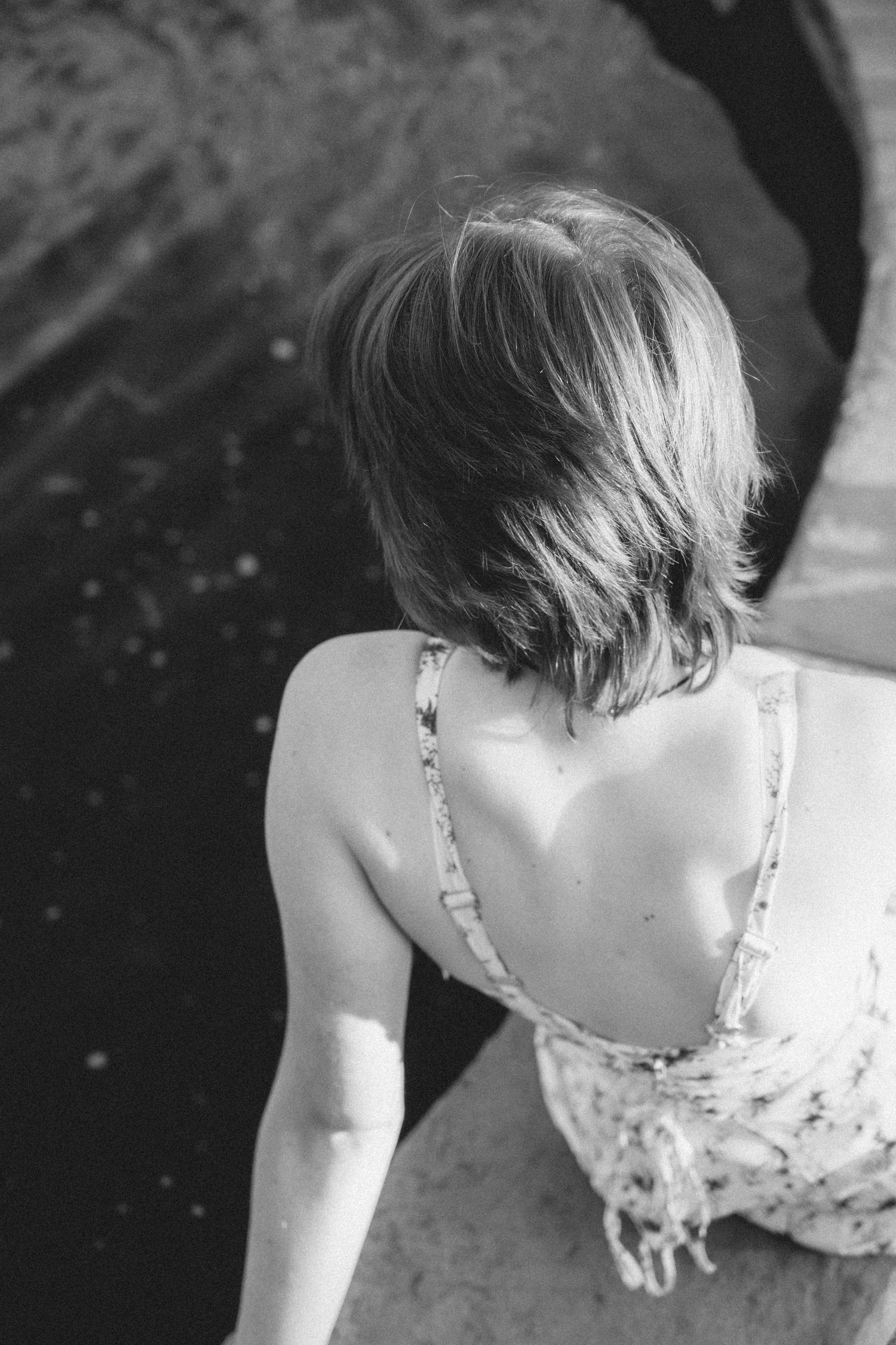 Black and white portrait showing back view of person in floral dress.