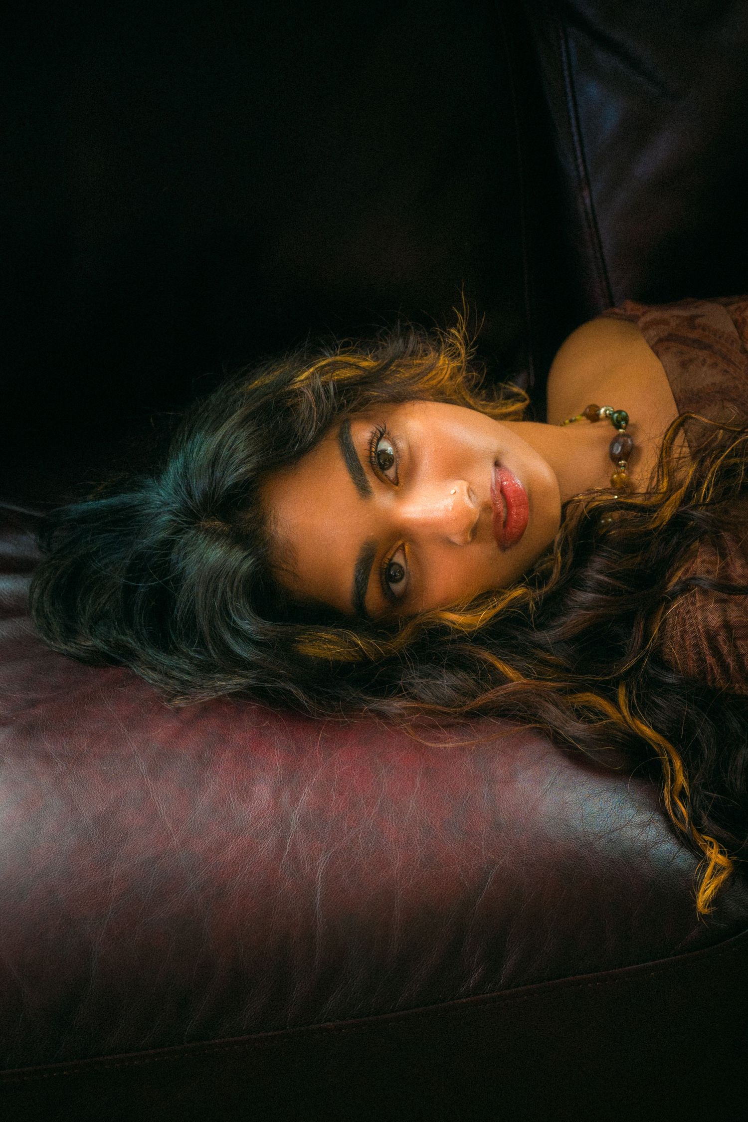 A moody portrait shot on a leather couch with dramatic lighting.