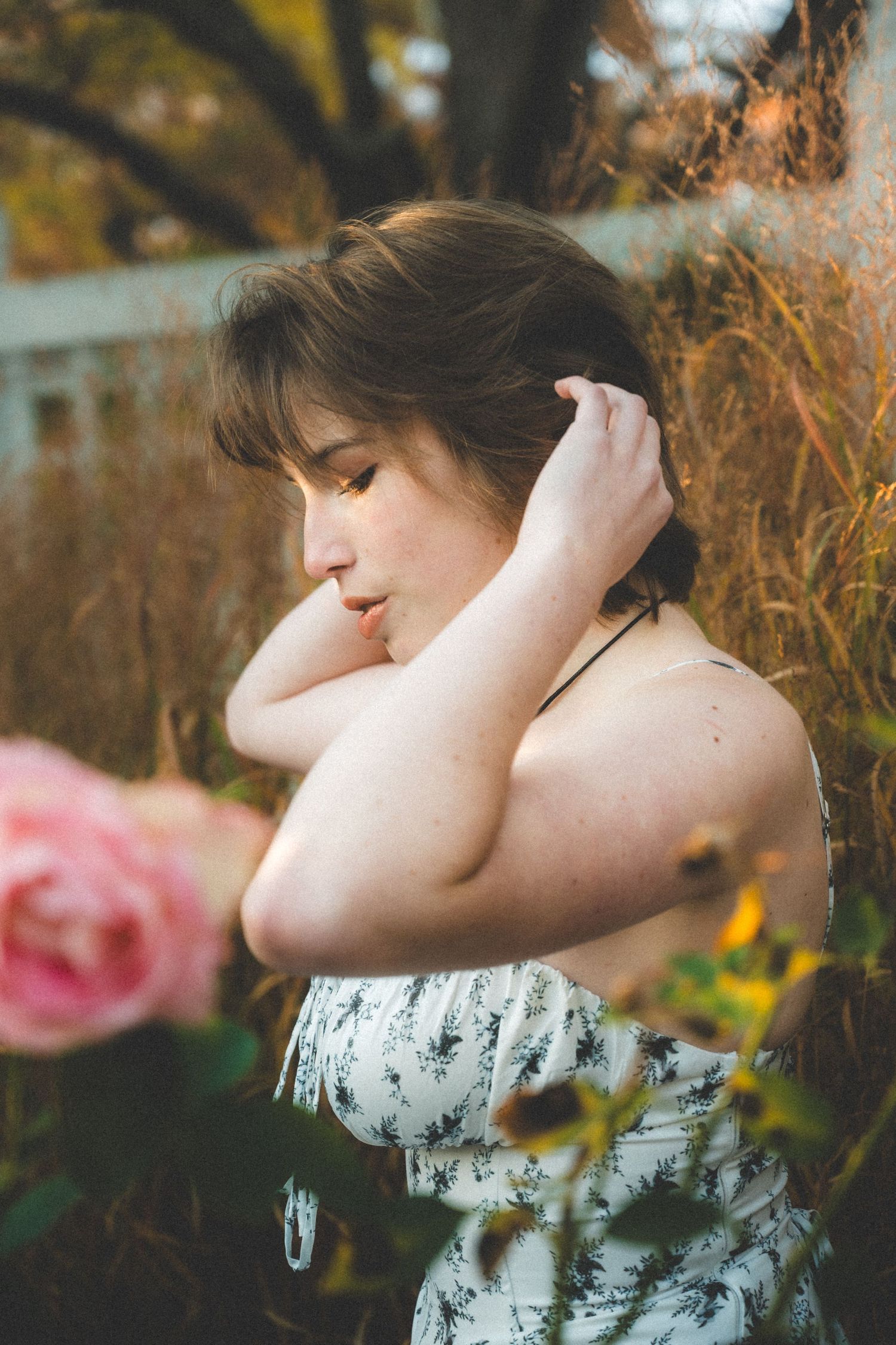 An autumn photoshoot featuring a white floral dress against golden foliage.