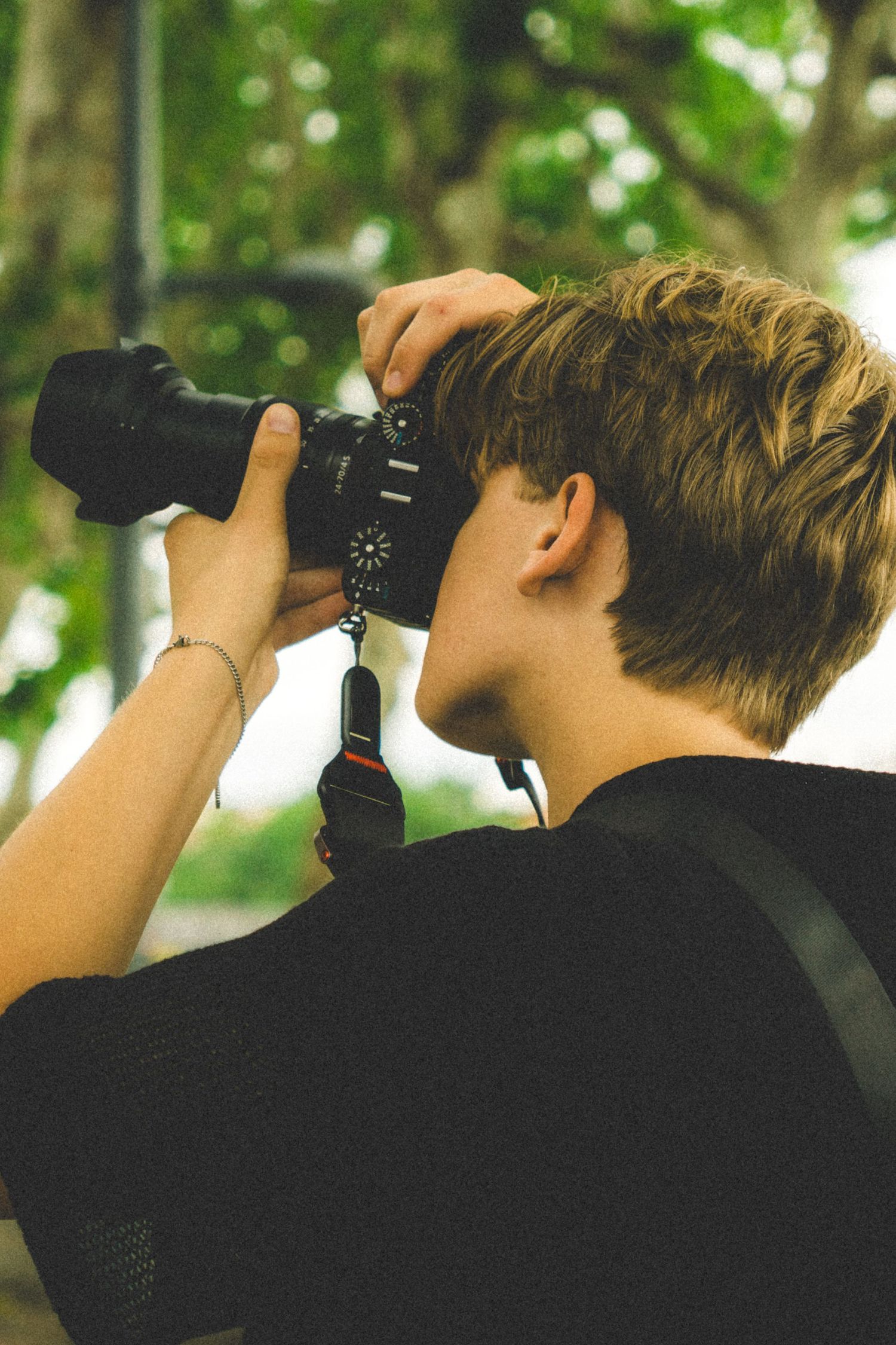 Someone looking through binoculars while wearing a dark jacket, photographed from behind.