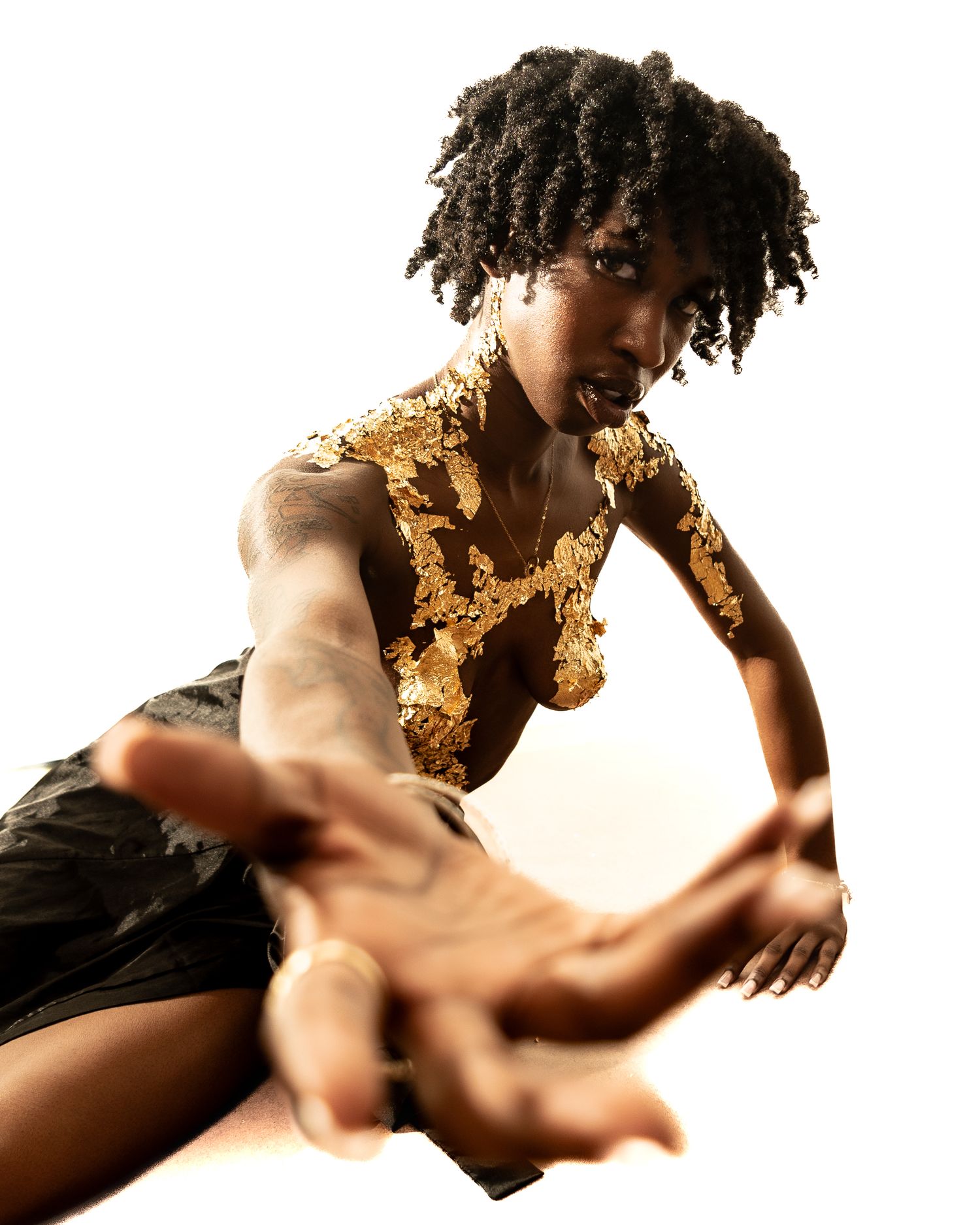 Dancer performs expressive movements with gold accents against white background.