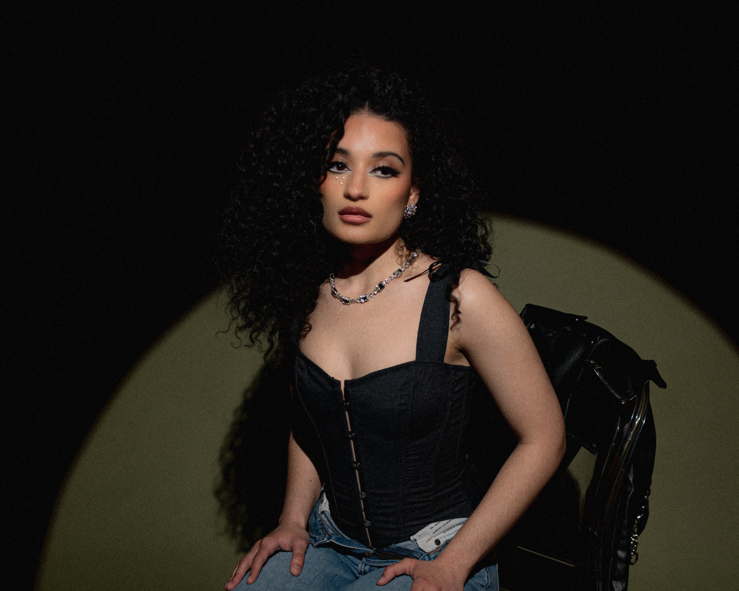 Moody fashion portrait in black corset and denim with dramatic lighting.
