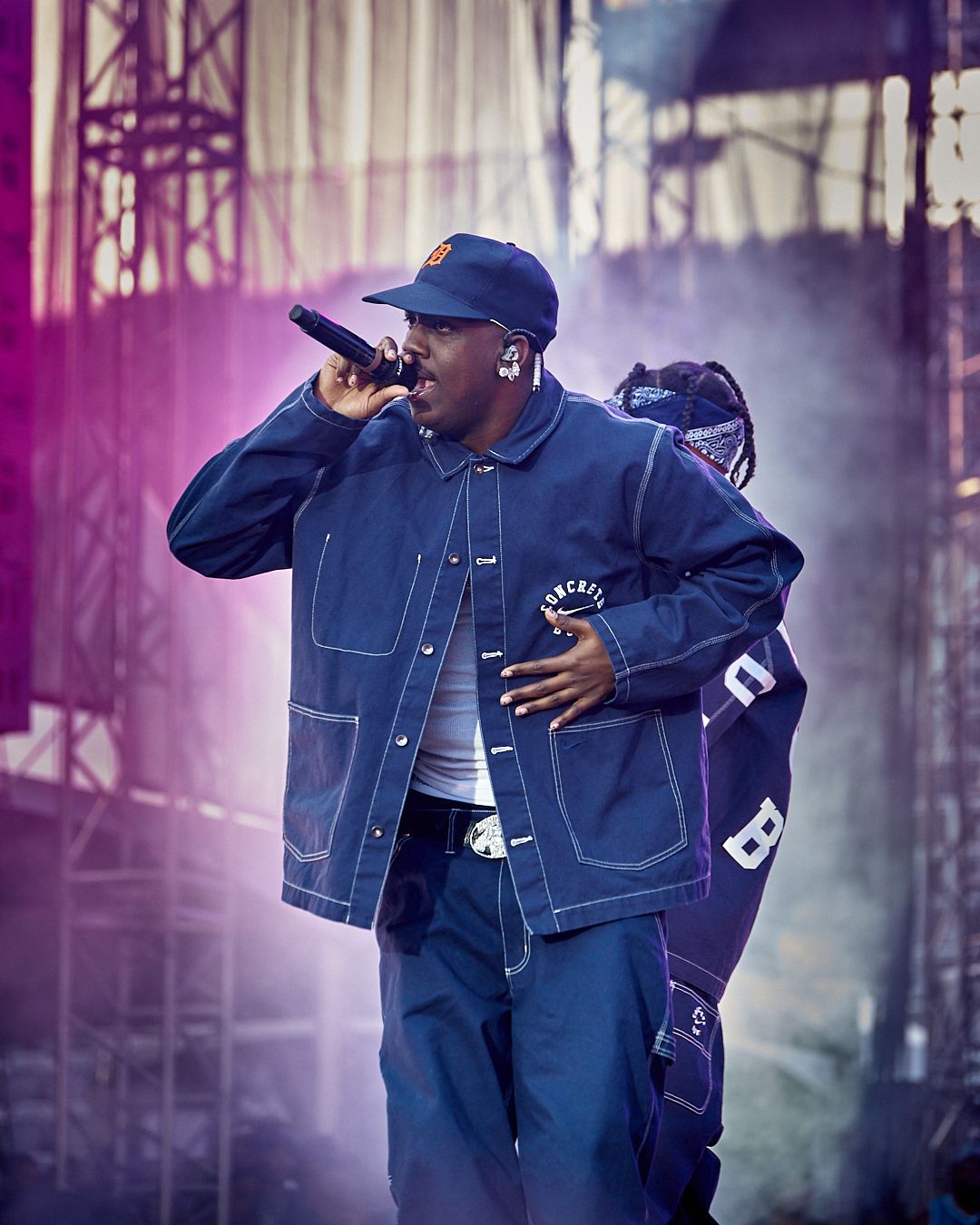 Performer in denim jacket energetically dancing on stage with purple lighting effects. concrete boys, lil yachty