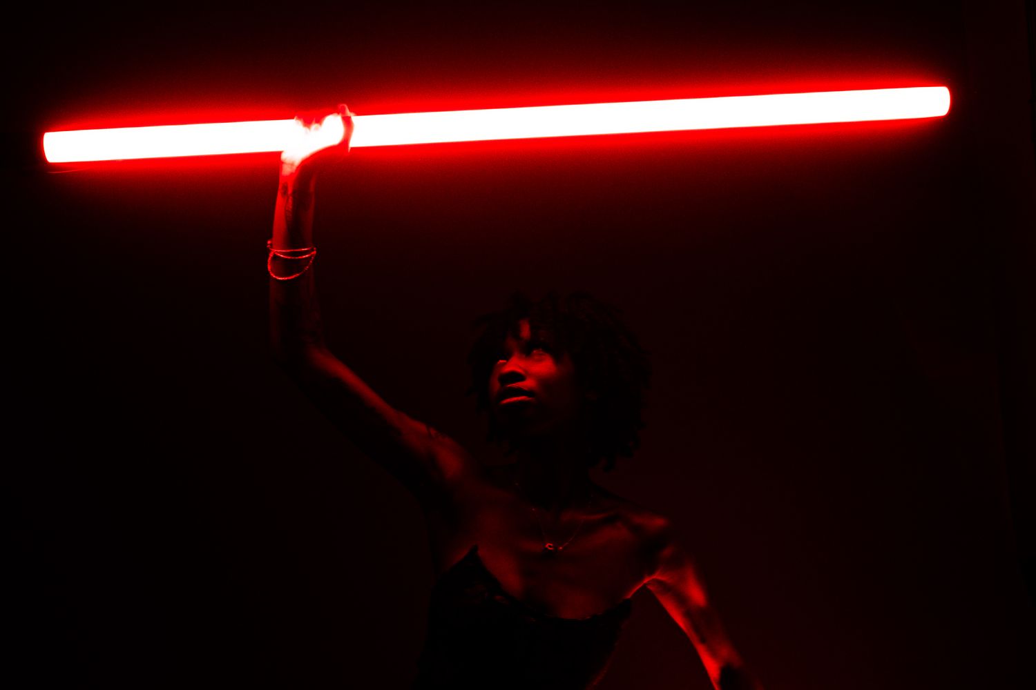 Red neon light installation creating dramatic shadows and atmosphere in dark space.