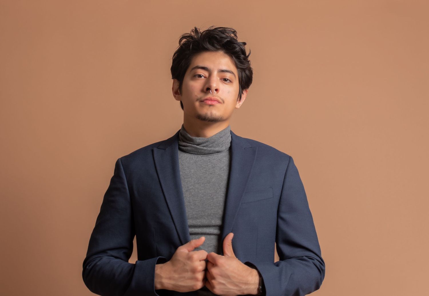 Professional business portrait in navy blazer and grey top against warm background.