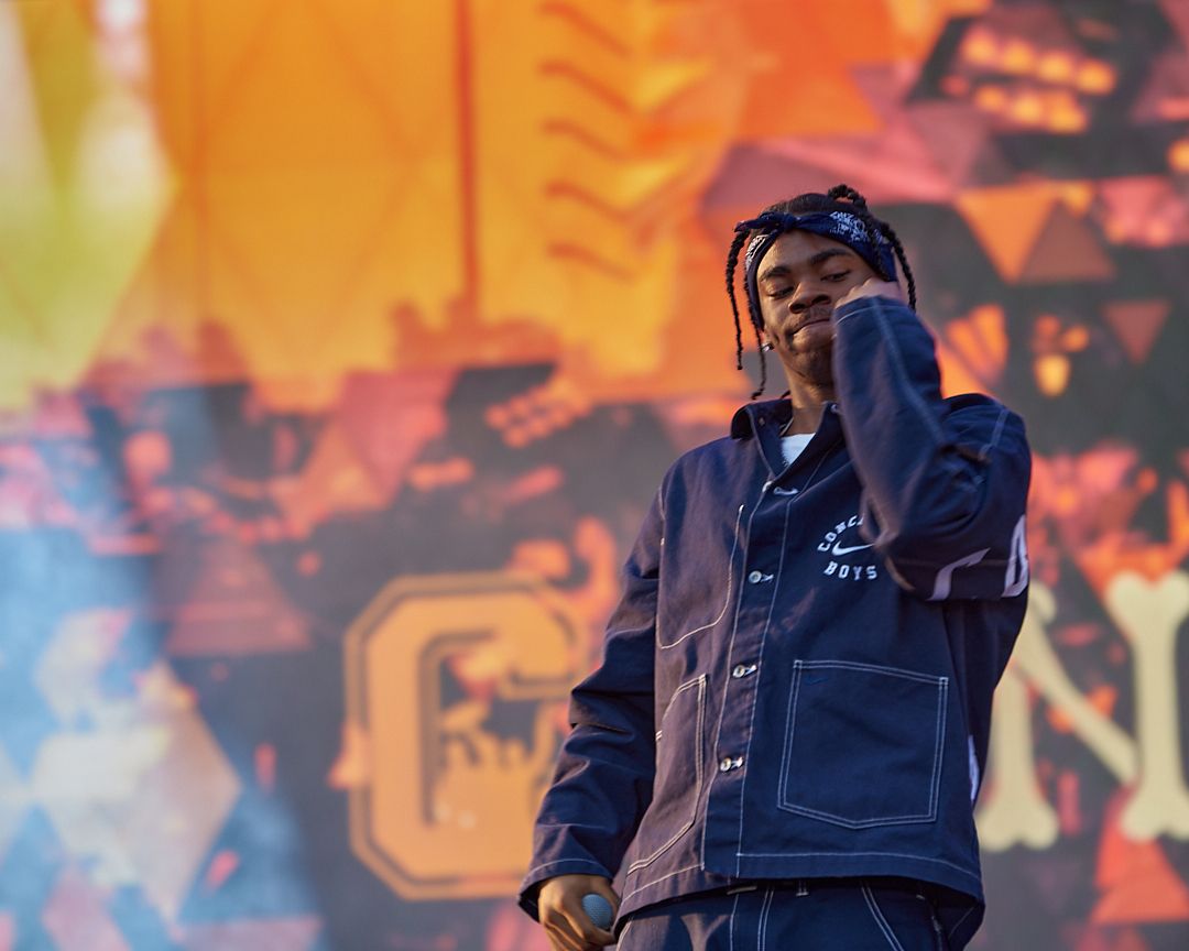 Stage performer in blue denim against vibrant orange and yellow backdrop. concrete boys