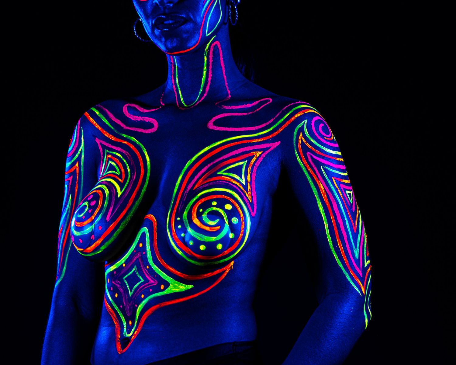 Abstract UV body art featuring swirling neon lines and patterns illuminated in blue light.