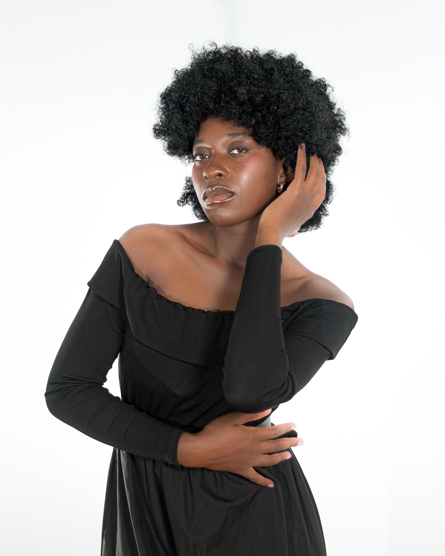 Expressive poses in black dress against white backdrop with natural afro hairstyle.
