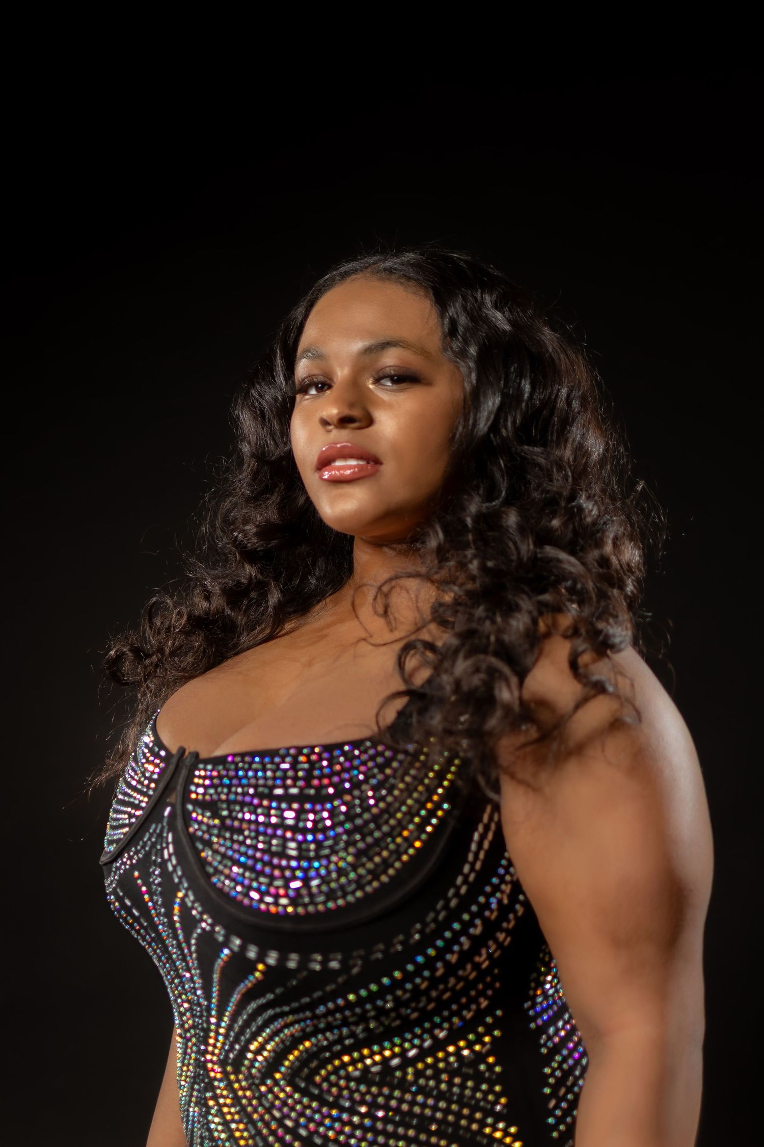 Close-up of sparkling beaded dress detail with dramatic studio lighting.