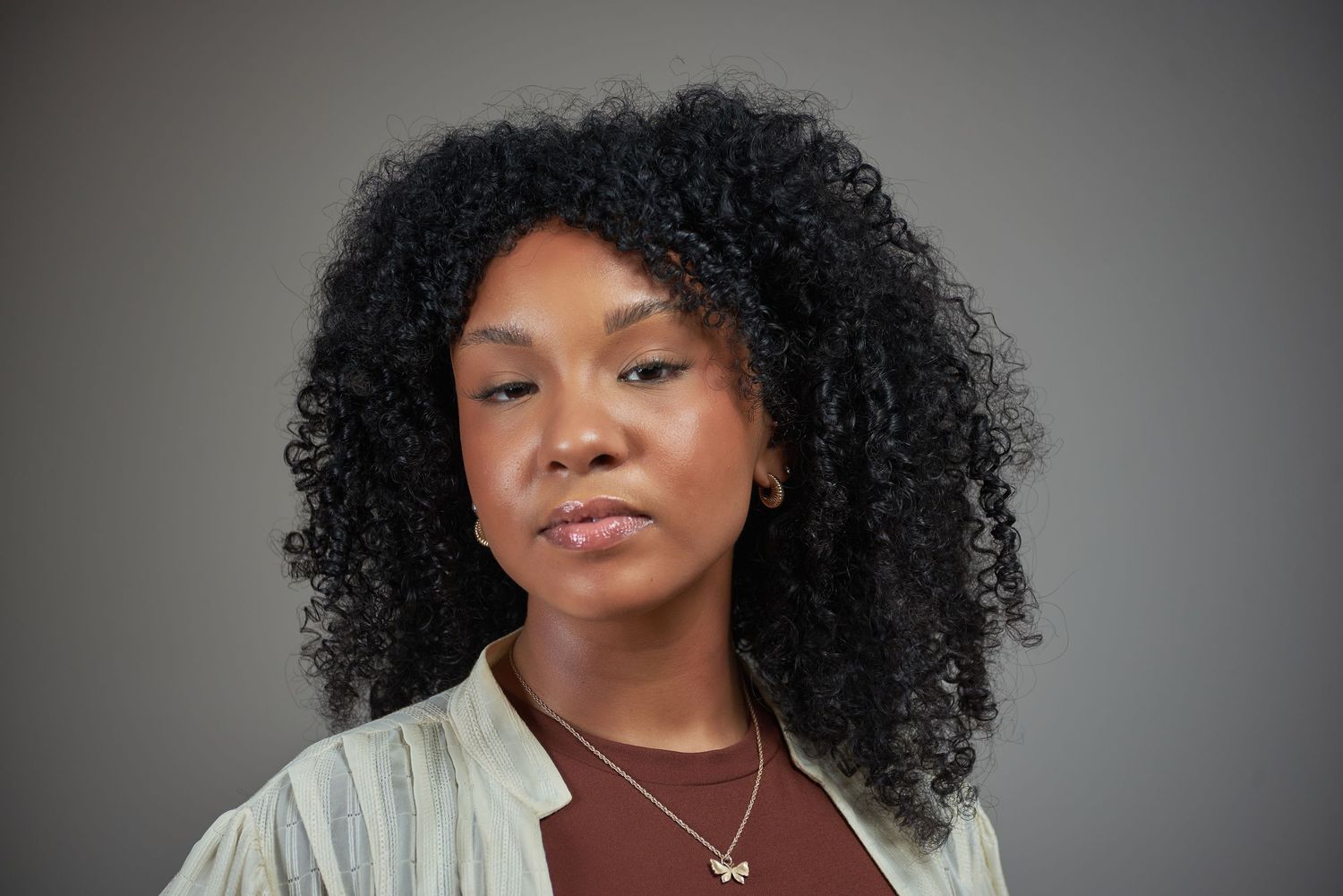 Professional headshots featuring natural curly hair and white clothing against a gray backdrop.