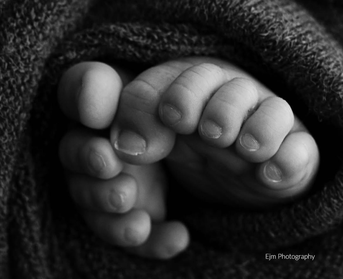 Black and white photo of newborn baby toes wrapped in a blanket.