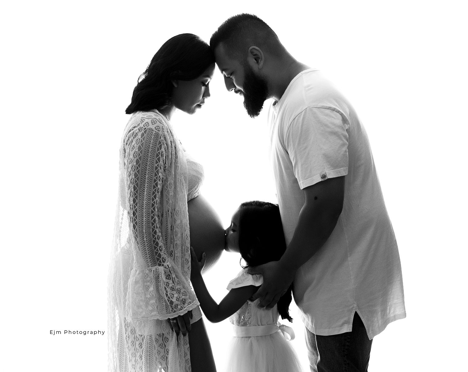 Pregnant mum with husband and daughter. All posed together while daughter kisses mums belly.