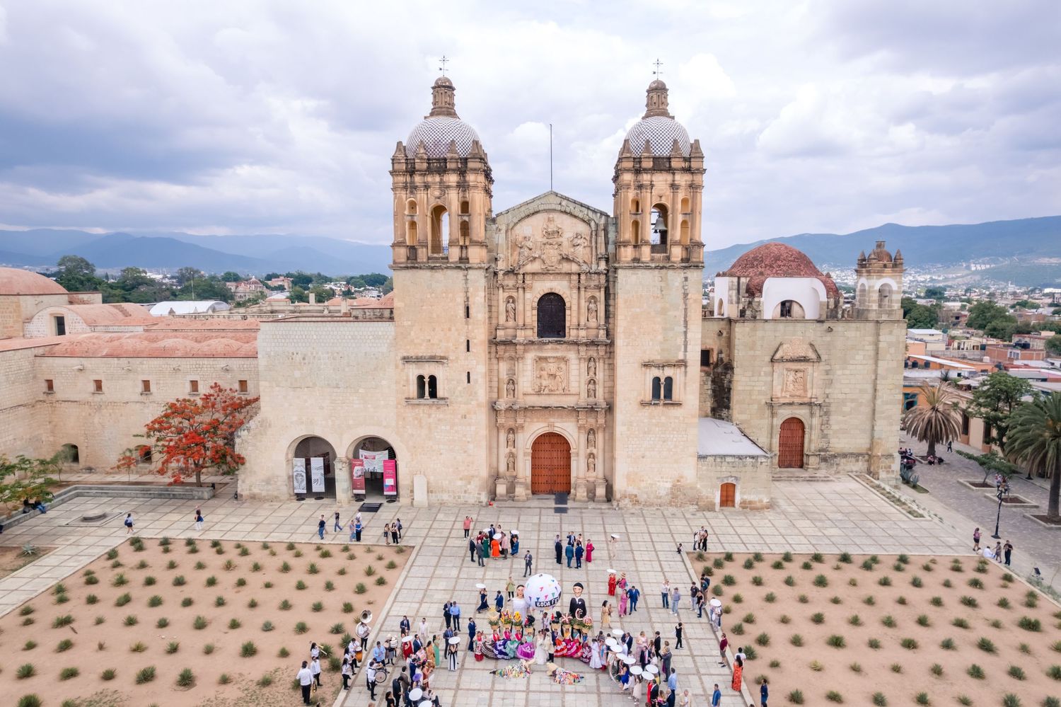 Aerial view of Santo Domingo de Guzman Church in Oaxaca, Mexico, with crowds gathered in the plaza below.
