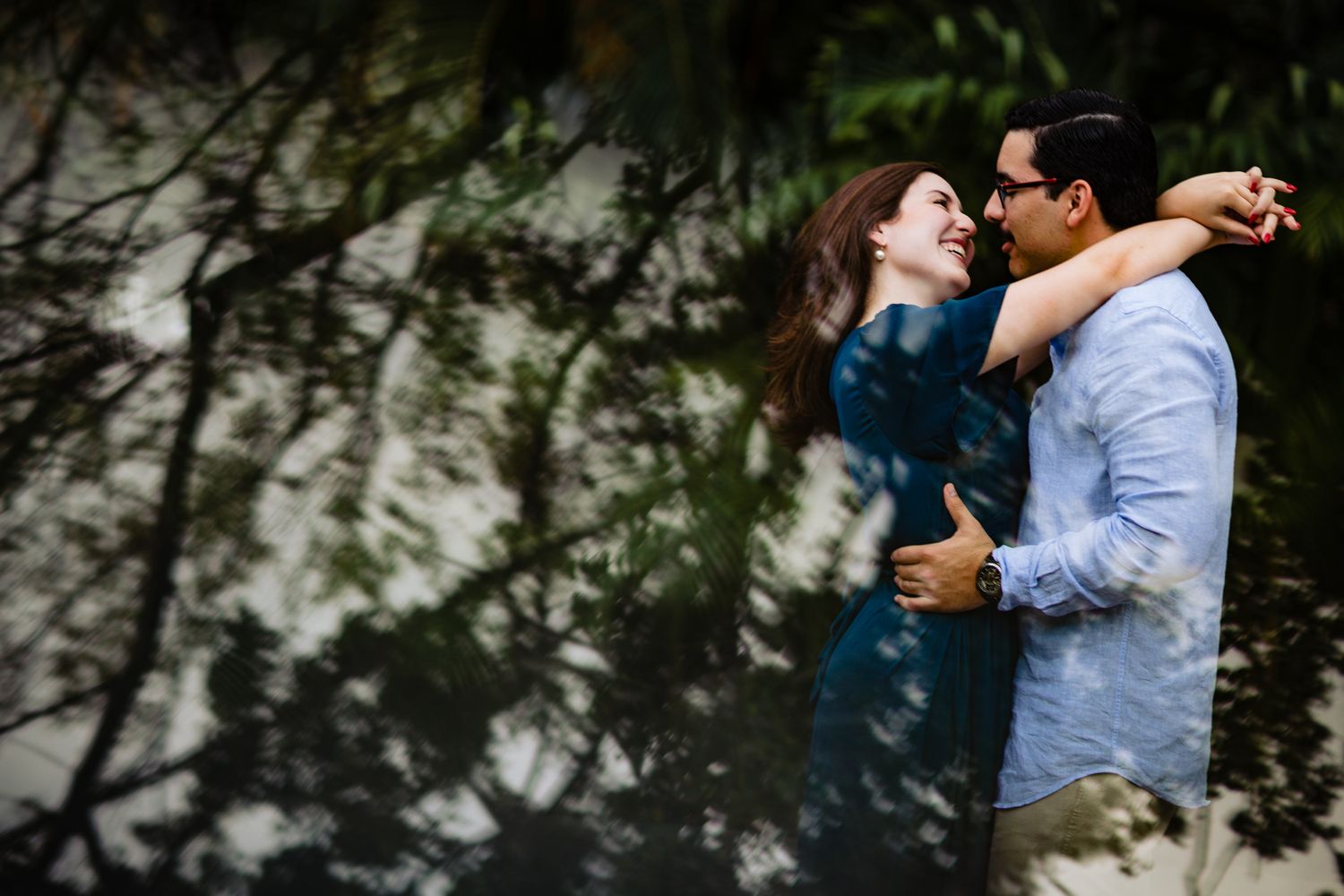 Romantic outdoor engagement photography session showing couples embracing under natural lighting and trees.