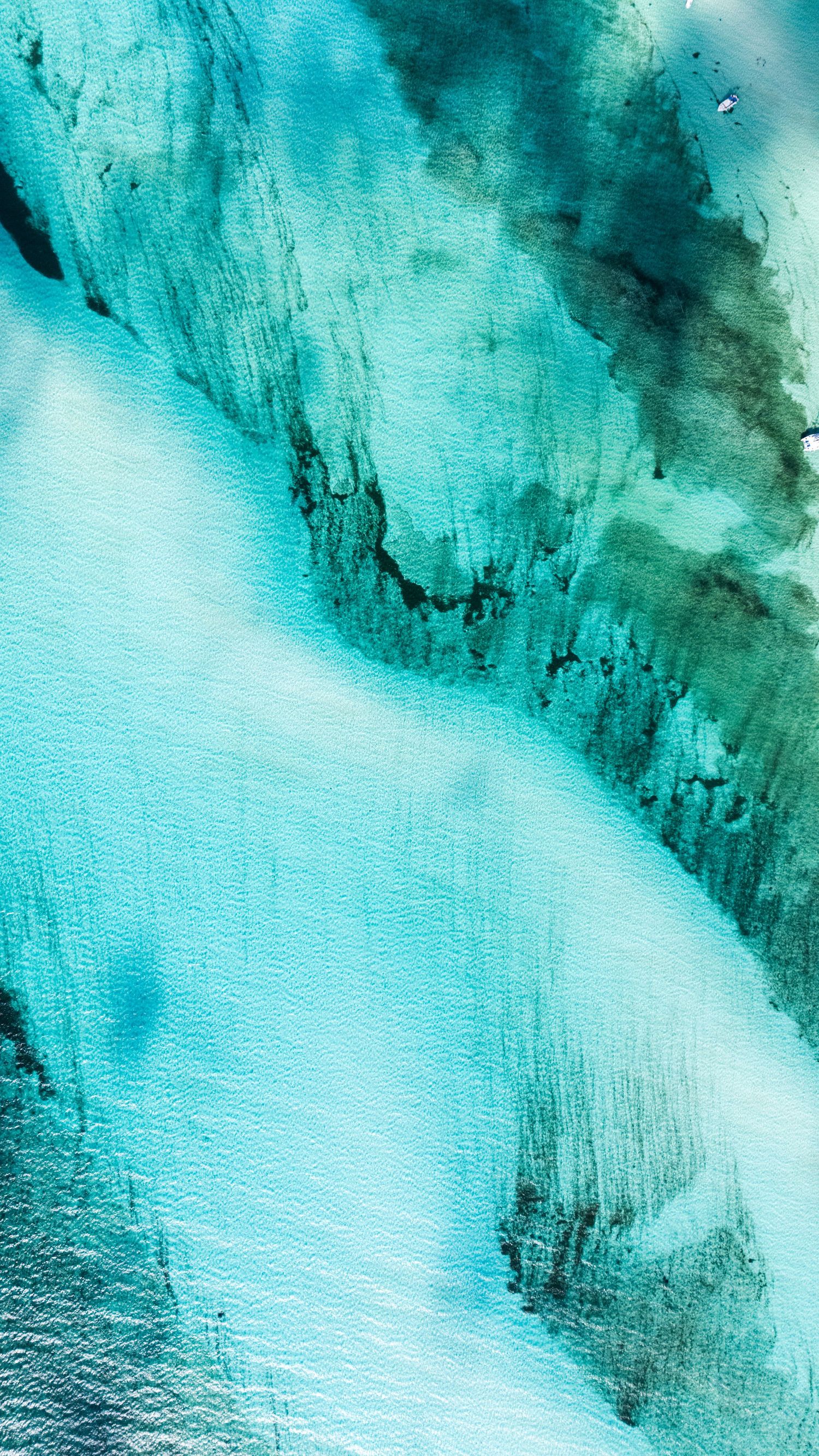 Aerial view of turquoise glacial ice formations and patterns creating abstract shapes in pristine snow and ice.