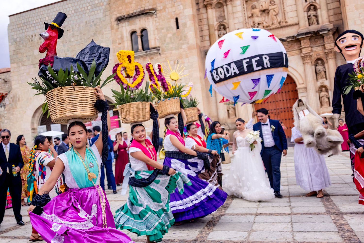 Colorful Mexican wedding procession with traditional Oaxacan dancers in vibrant skirts outside a historic church.