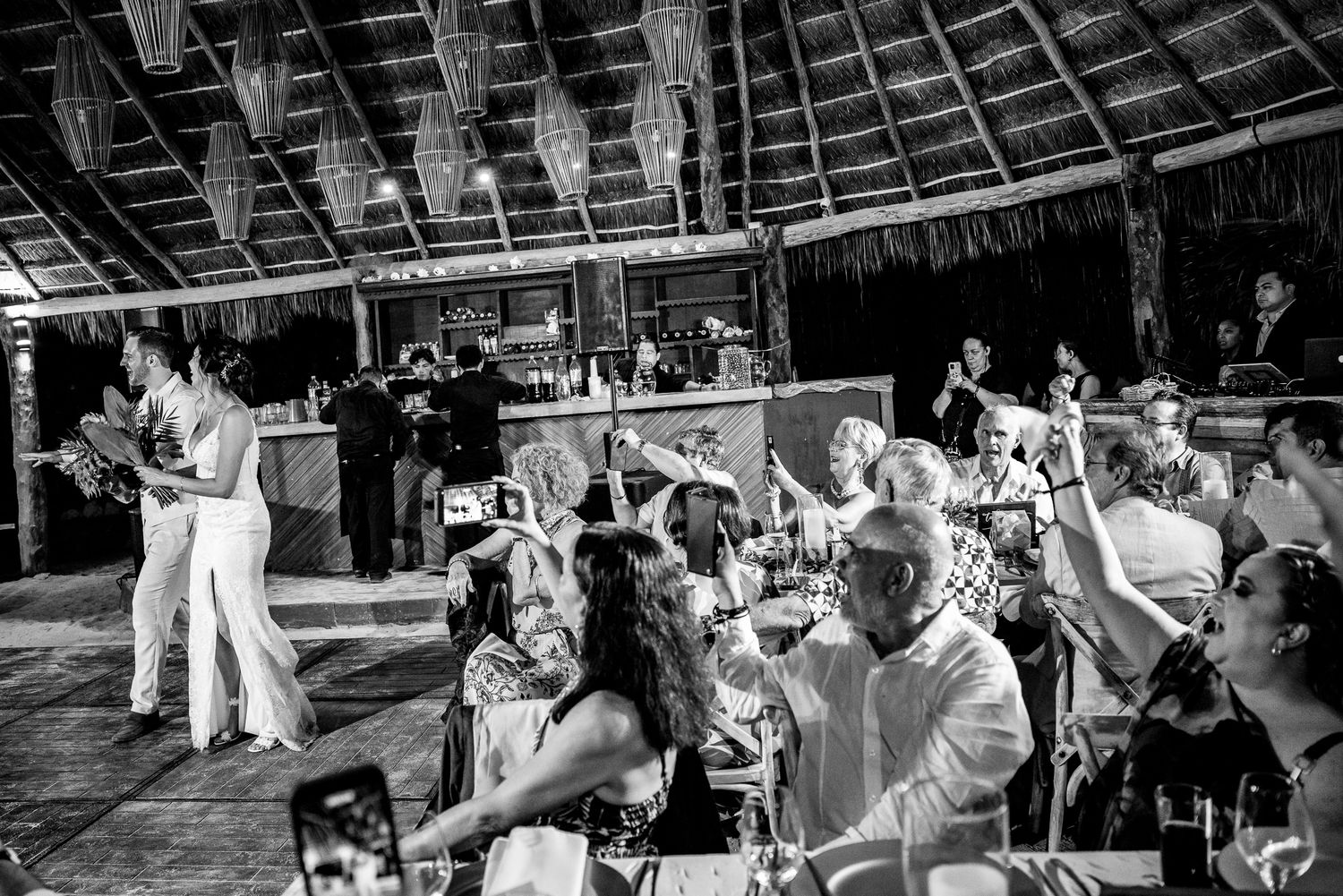 Black and white photo of guests celebrating at a tropical outdoor wedding reception venue.