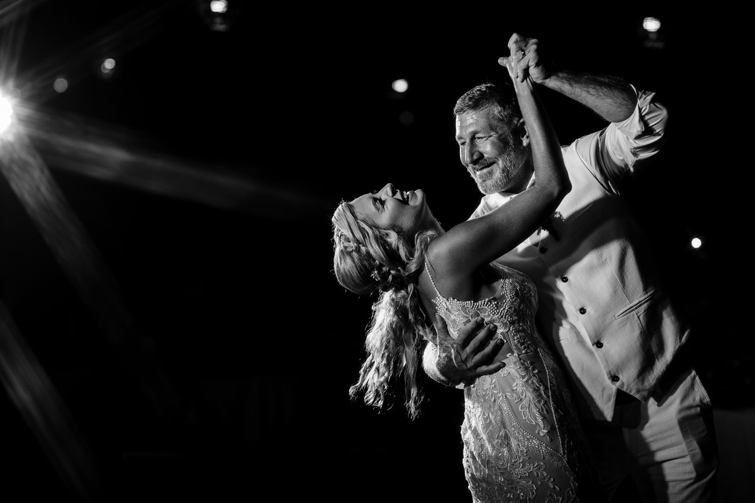 A couple performs an elegant dance move under dramatic spotlighting at wedding. destination wedding couple portraits in cozumel