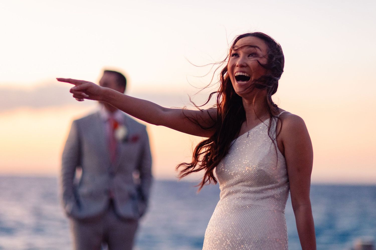 A joyful couple shares a romantic moment on the beach at sunset during their wedding celebration.