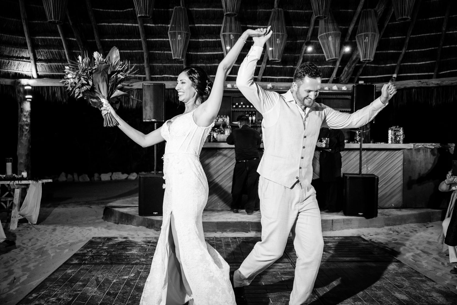 Black and white photo of a bride and groom joyfully dancing at their wedding reception.