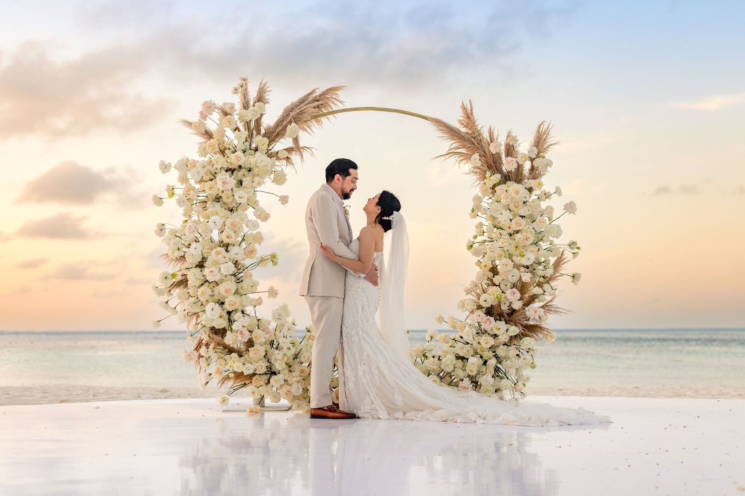 A romantic beach wedding scene with white floral arrangements. destination wedding couple portraits in cancun Mexico artistic photographer