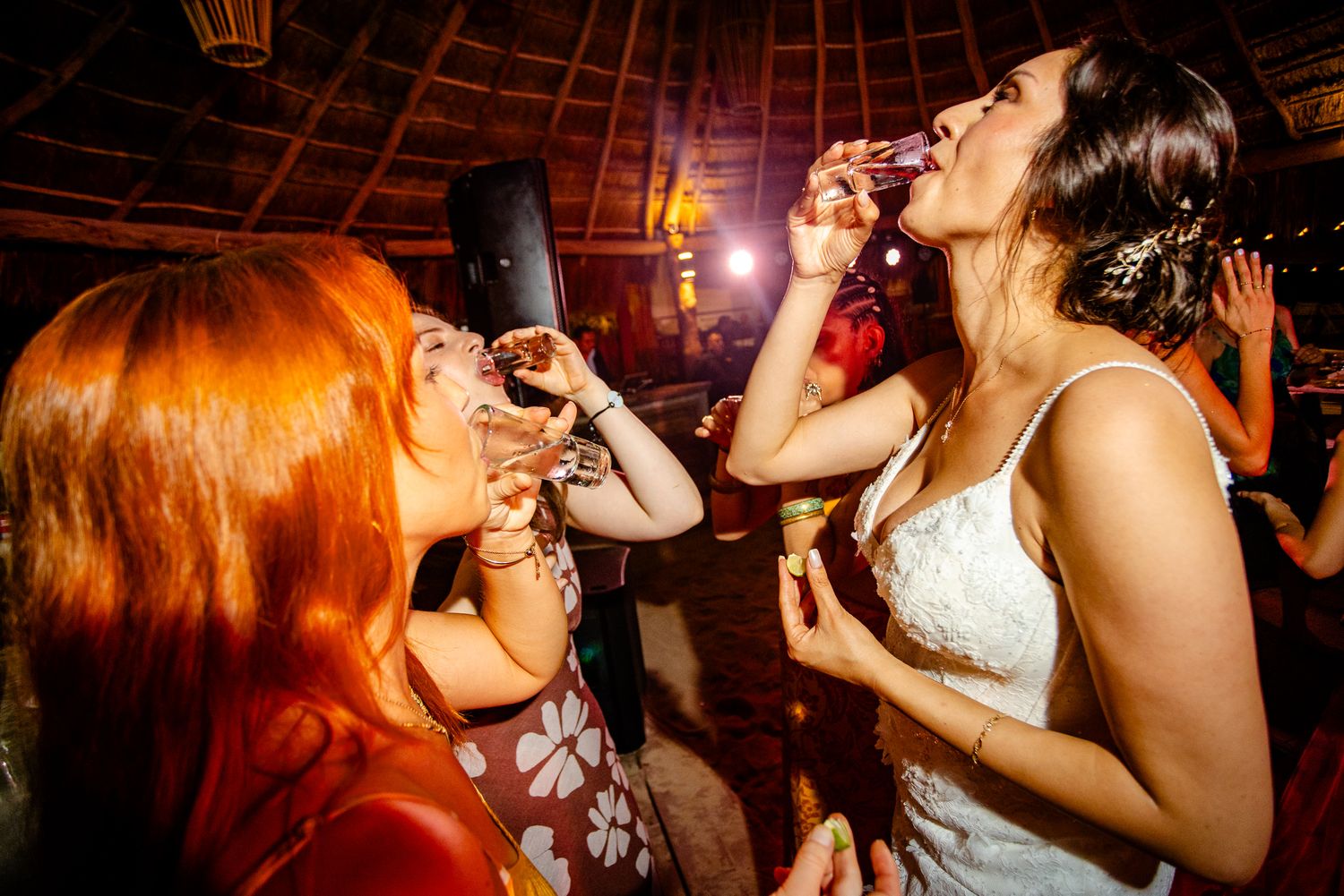 Bride and guest drink shots together at a lively wedding reception party.