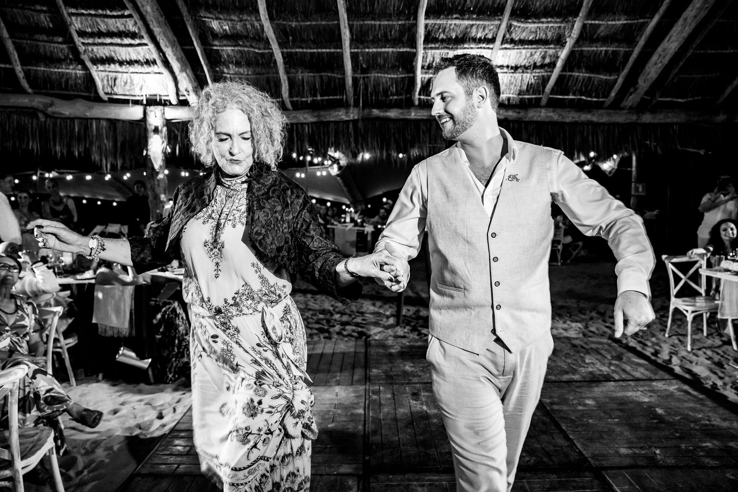Couple dancing joyfully at a wedding reception in black and white photo.