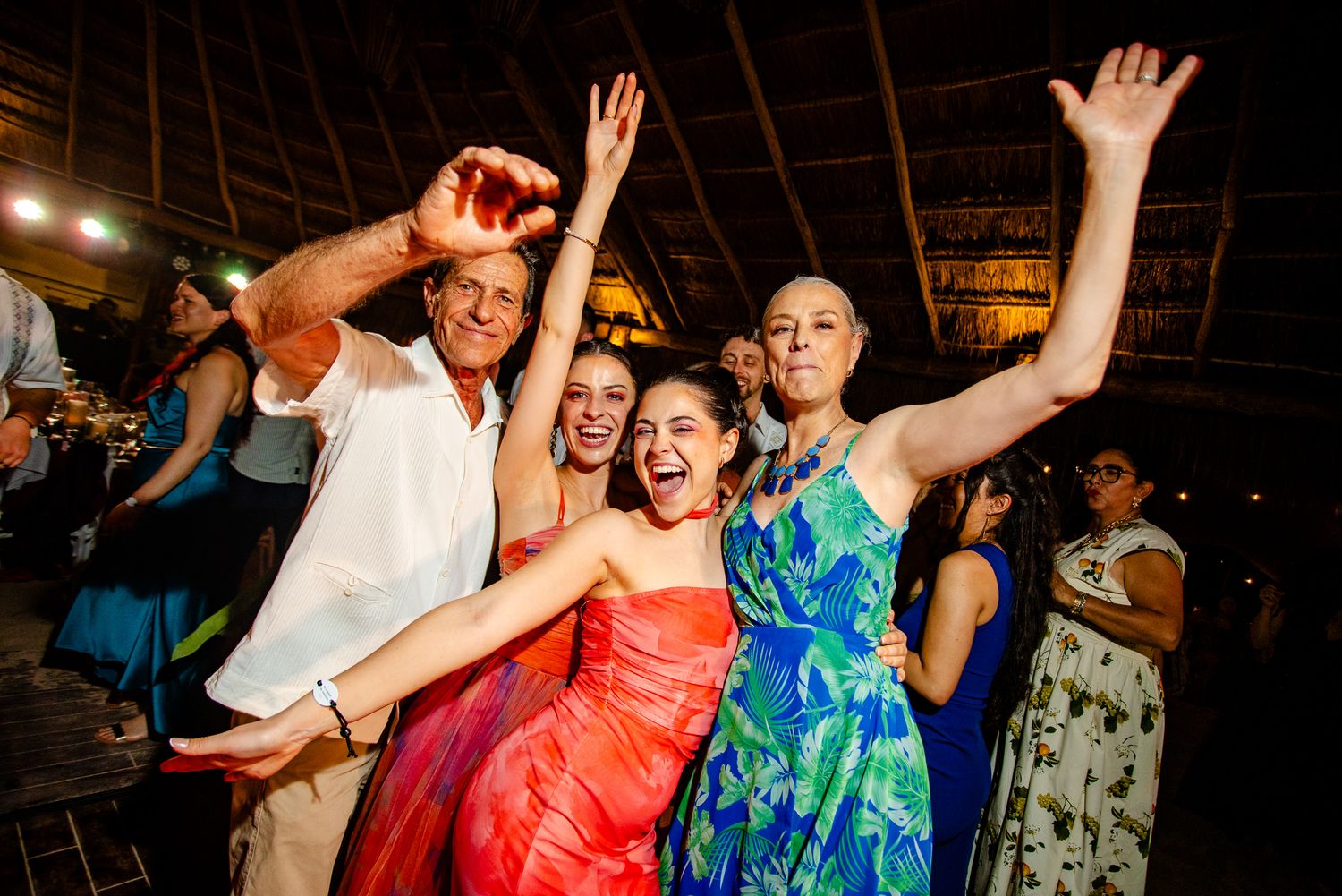 Group of joyful guests dancing and celebrating at a tropical wedding reception party.