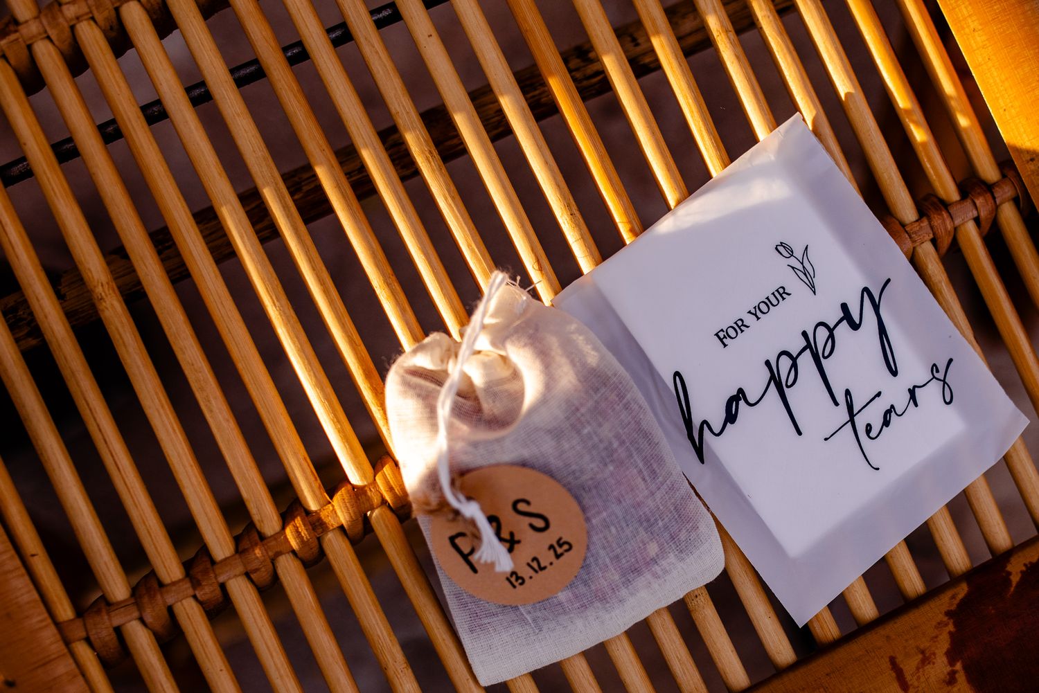 Small linen bag with wooden tag and happy tears card, perfect wedding favor gift on bamboo surface.