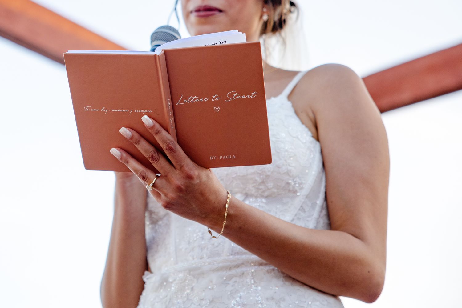 Woman in white dress reads from a brown 