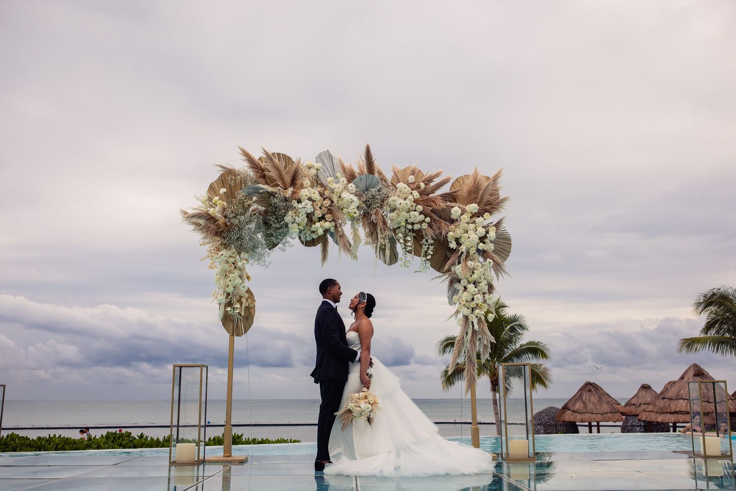 Couple kissing under floral arch at oceanfront wedding ceremony Cancun Wedding Photographer, Destination Wedding Cancun,