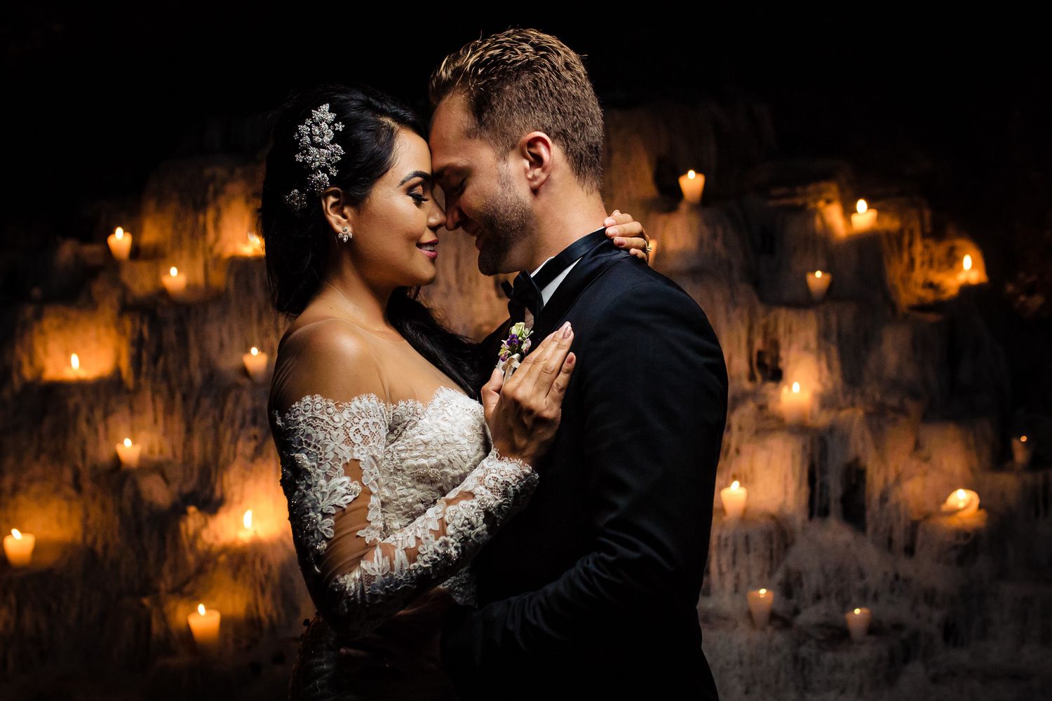 Romantic couple embracing in intimate candlelit setting with warm glowing ambiance.