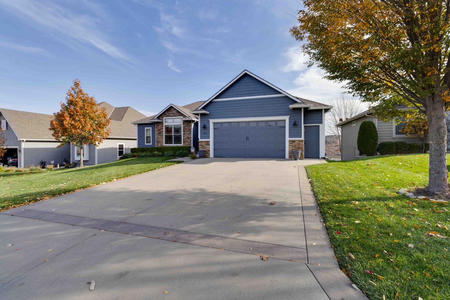 Navy blue single-story home with two-car garage and manicured lawn on suburban street.