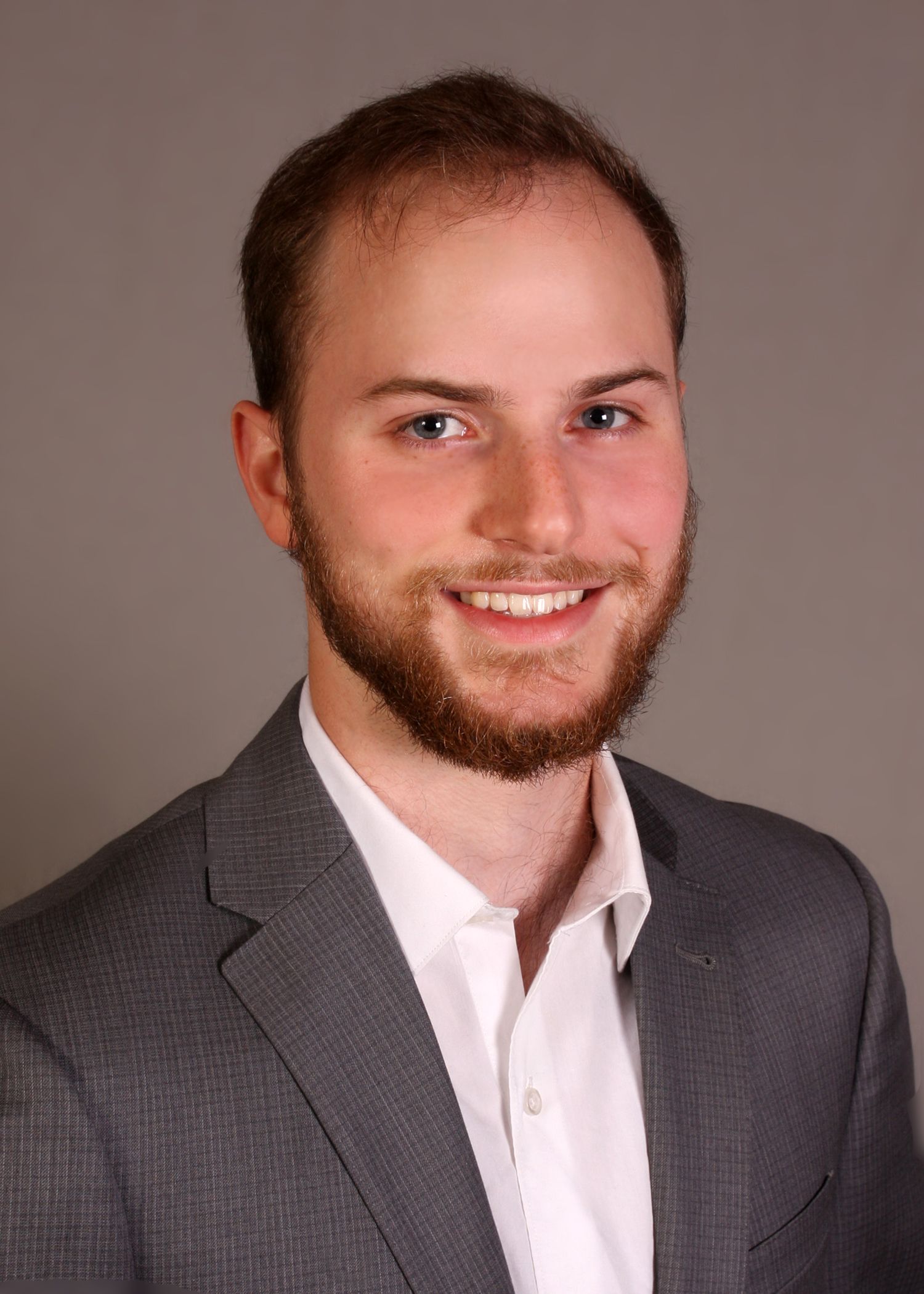 Professional headshot of a smiling person in business attire against a neutral background.