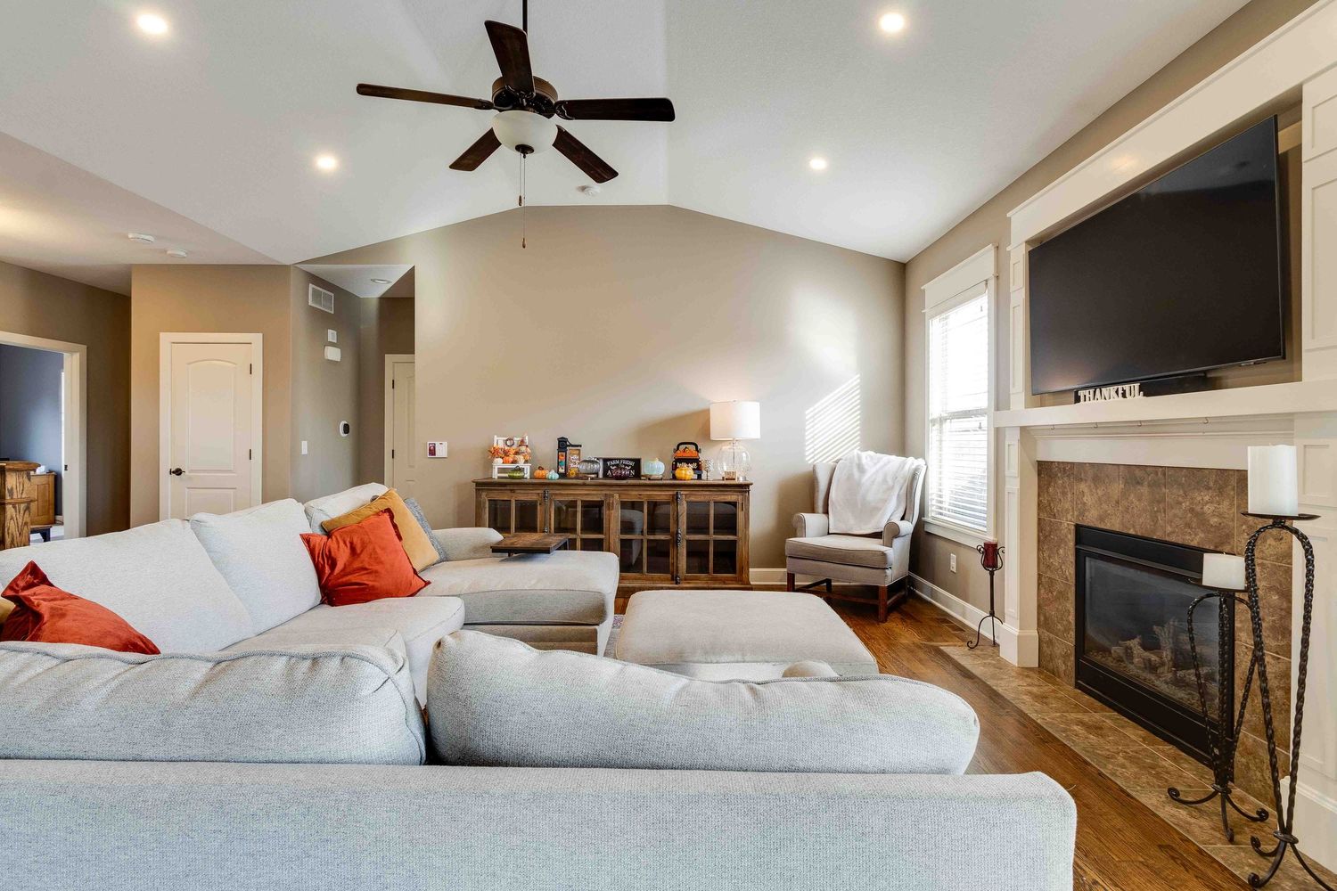 Contemporary living room with sectional sofa, fireplace, and mounted TV in neutral tones.