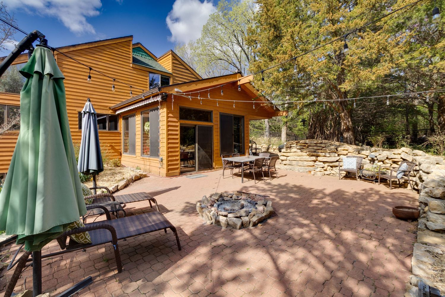 Spacious outdoor living area with stone fire pit and comfortable lounge seating at a log cabin.
