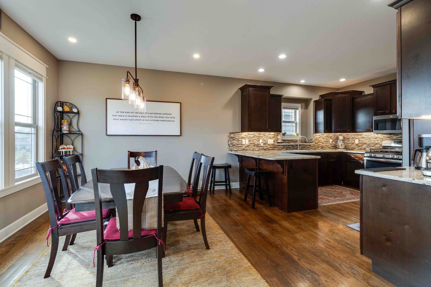 Open concept dining and kitchen area with dark wood cabinetry and hardwood flooring.