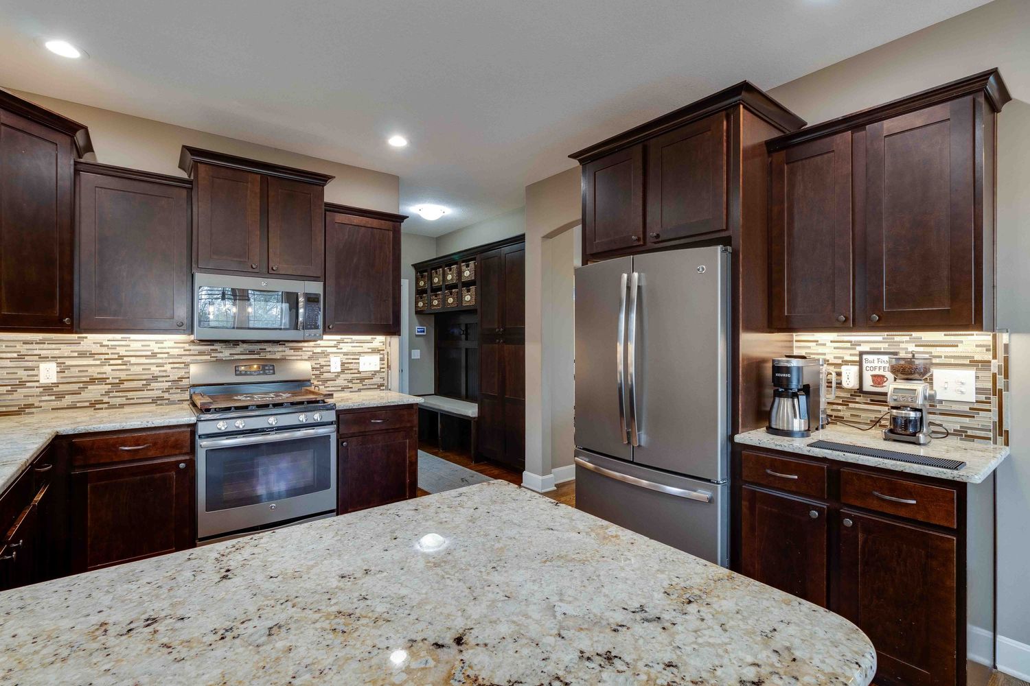 Luxury kitchen featuring dark wood cabinets, granite countertops, and stainless steel appliances.