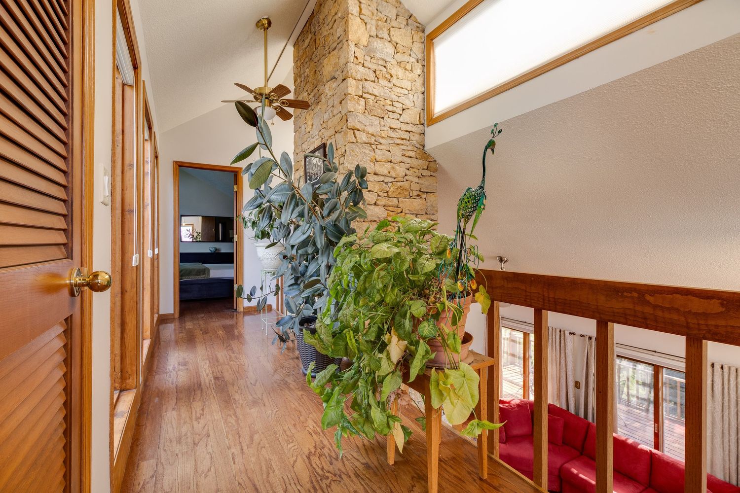 Hallway with wood paneling, stone accent wall, and indoor plants leading to living space.