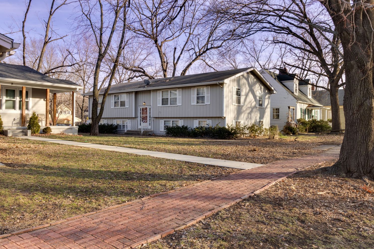 White ranch-style house with brick pathway and bare trees in winter setting.