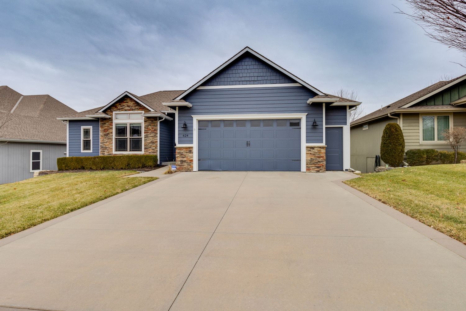 Blue residential home with stone facade and attached garage viewed from the driveway.