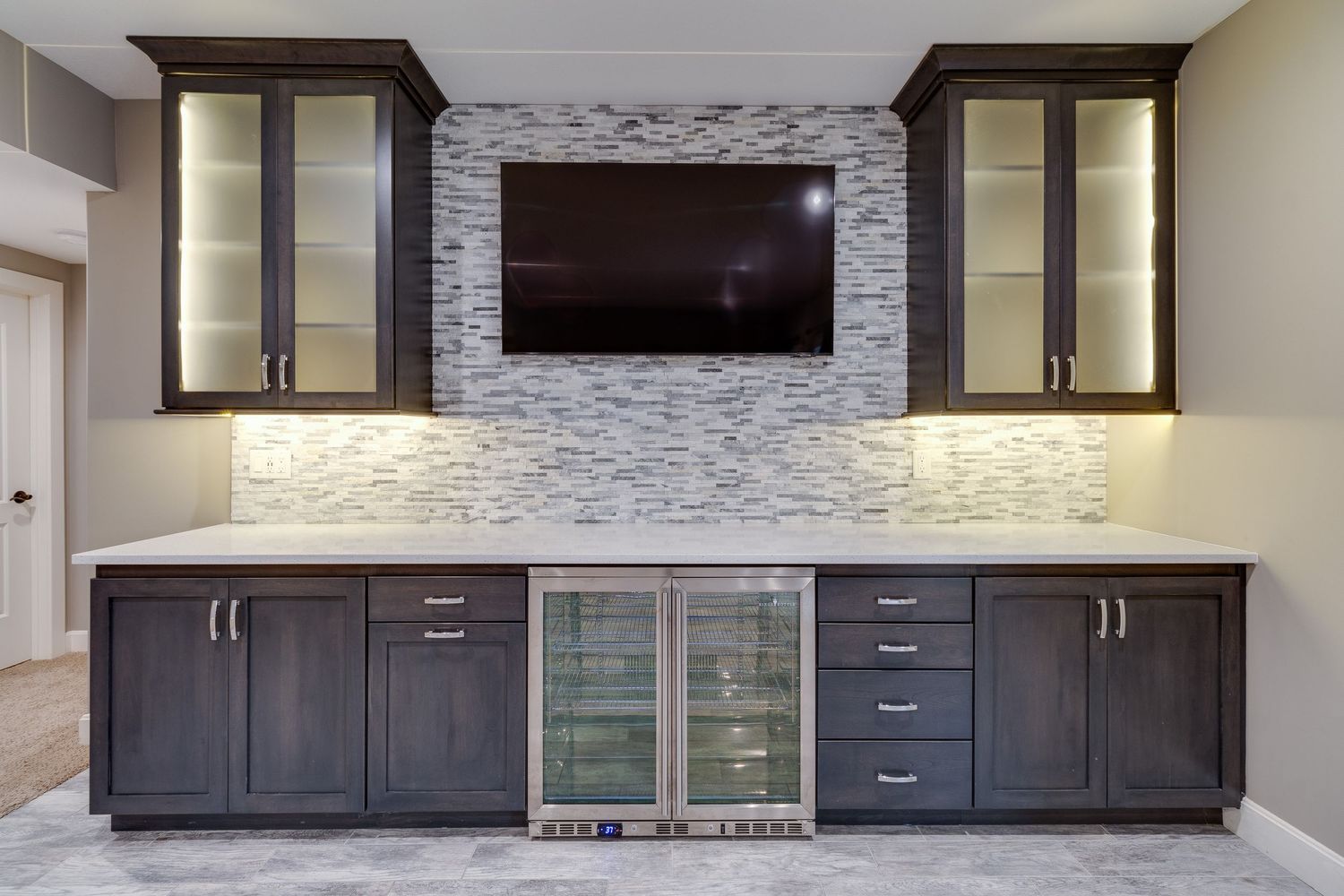Entertainment center with stone accent wall, built-in cabinets, and wine refrigerators.