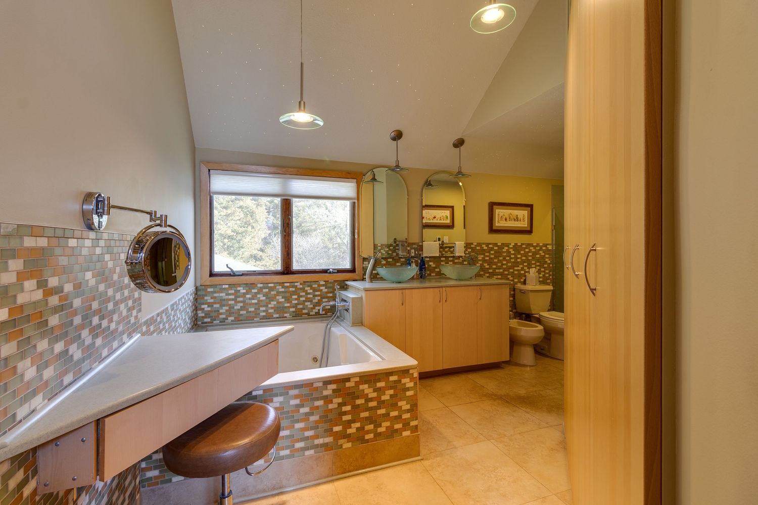 Modern bathroom with pebble-tiled walls, built-in vanity, and natural lighting from window.
